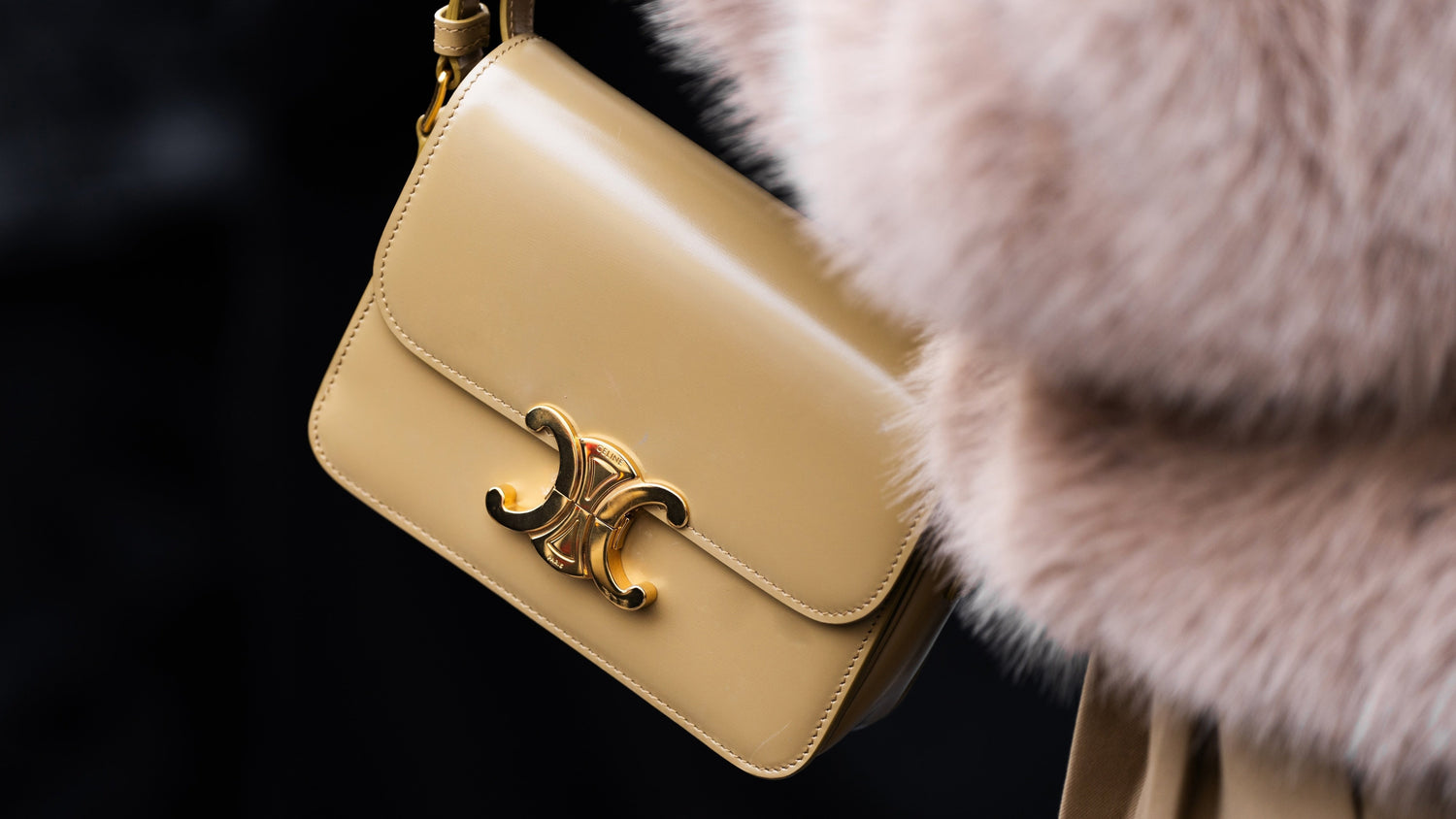 Beige handbag with gold clasp on a dark background